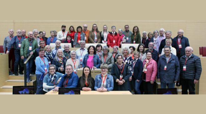 Auf den Stühlen im Plenarsaal Platz genommen